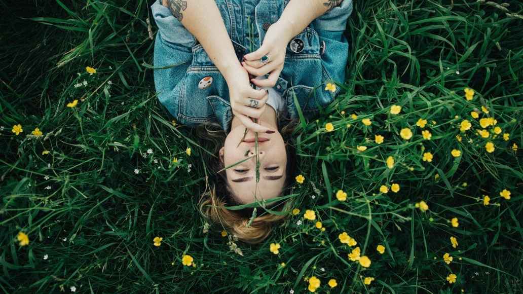 Person lying in grass surrounded by flowers